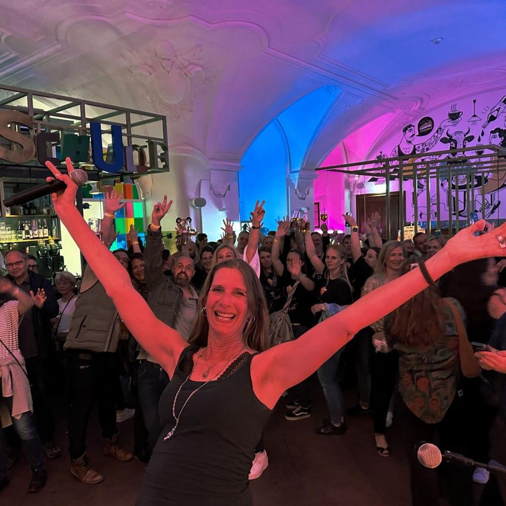 Stephanie von JustBrill! reißt beide Arme in die Lusft, hinter ihr tut das Publikum selbiges